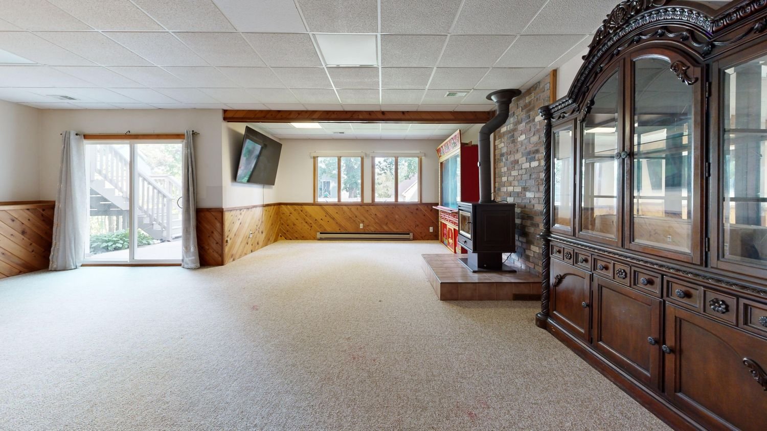 Finished basement with wood panelling, a fireplace and daylight windows