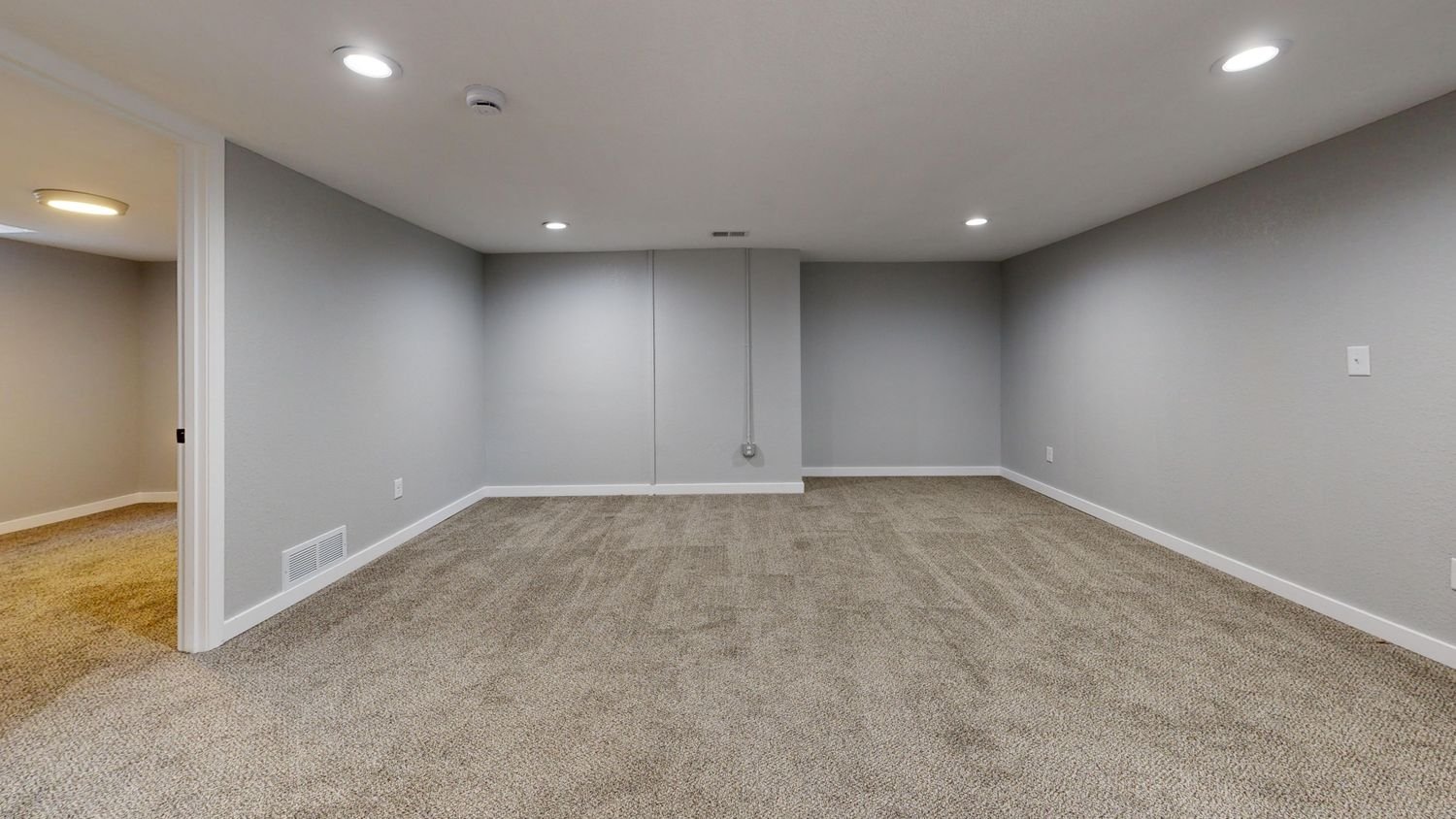 Open basement room with neutral walls and new carpet, ready to finish