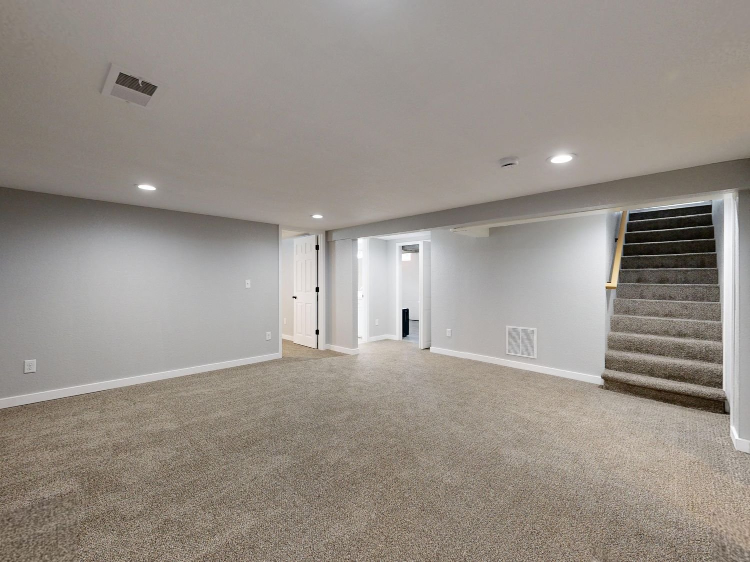 Empty basement with beige carpet and freshly painted white walls