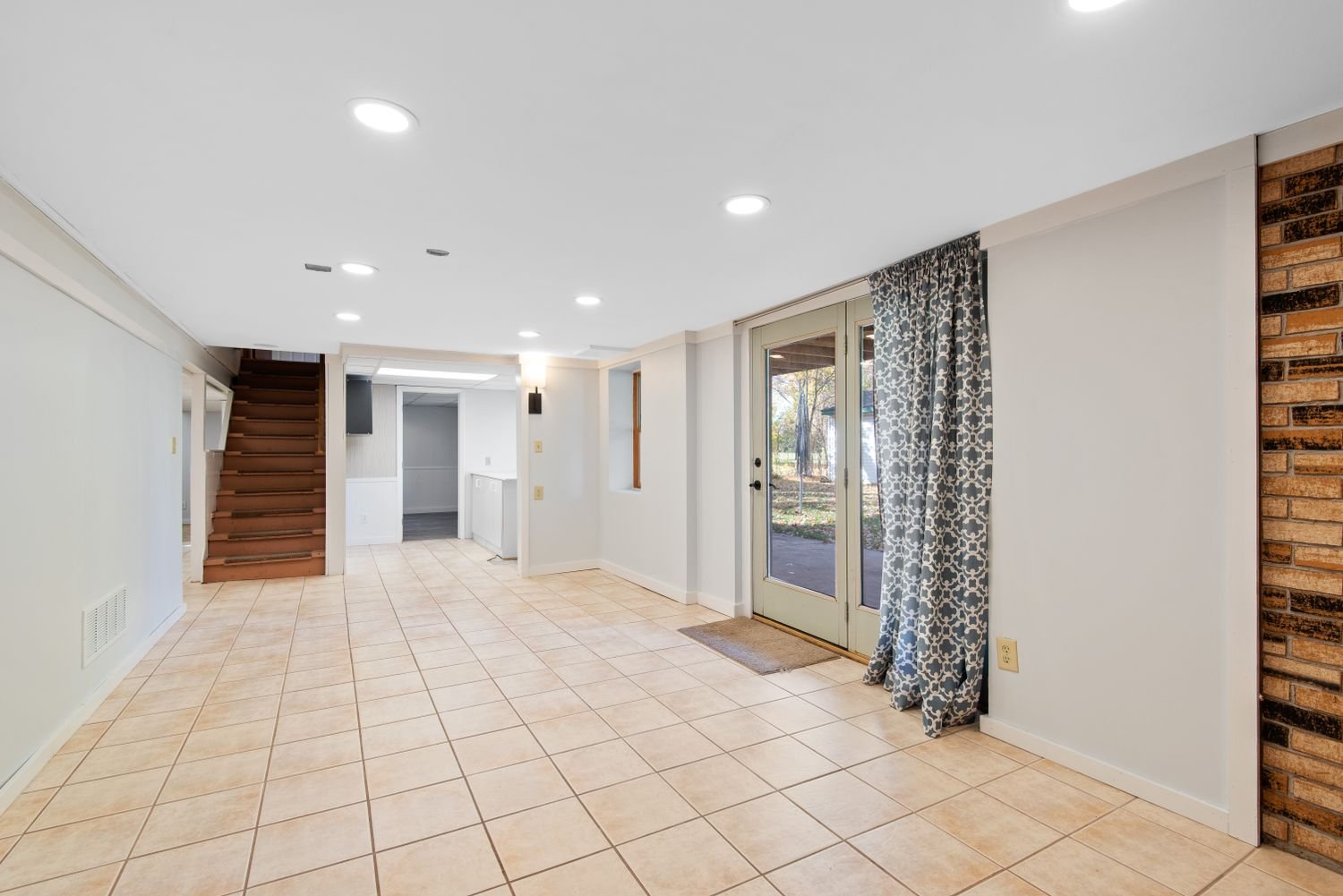 Bright basement with tile flooring and glass doors