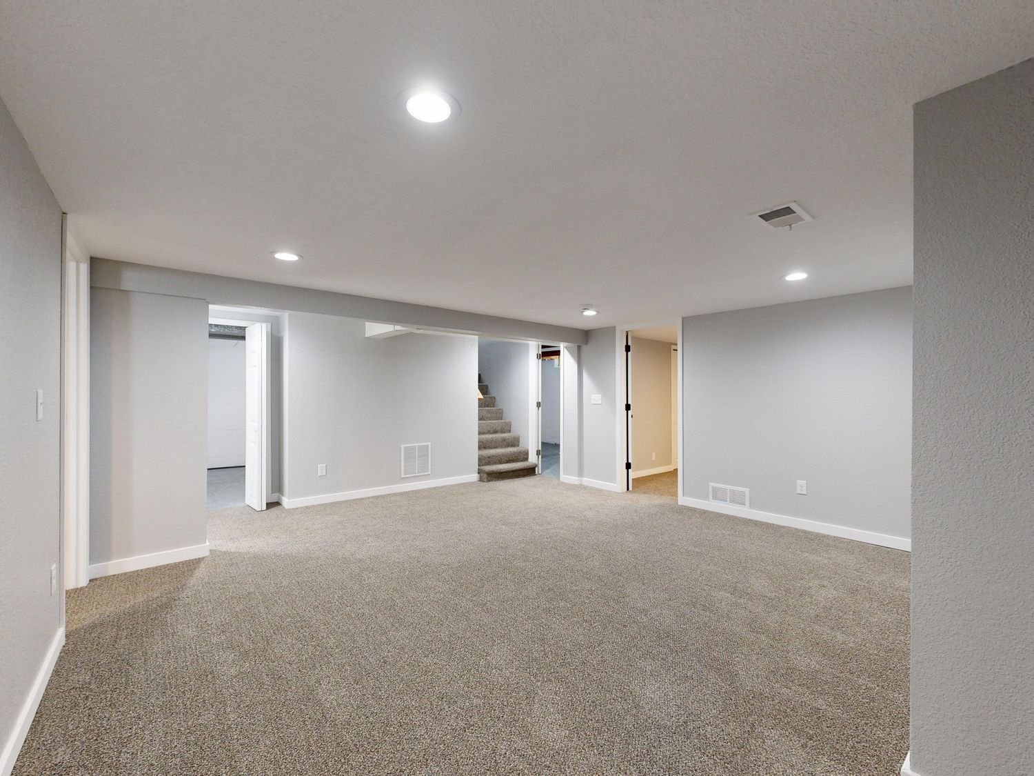 Spacious finished basement with neutral decor and carpet flooring