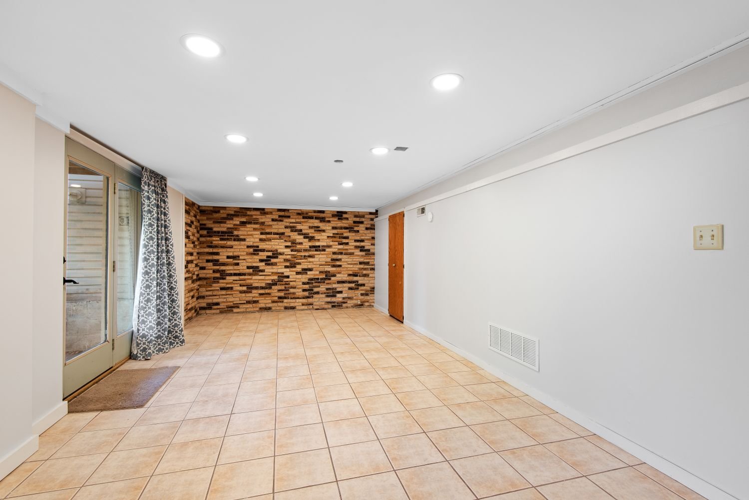 Basement with a brick accent wall and tiled flooring