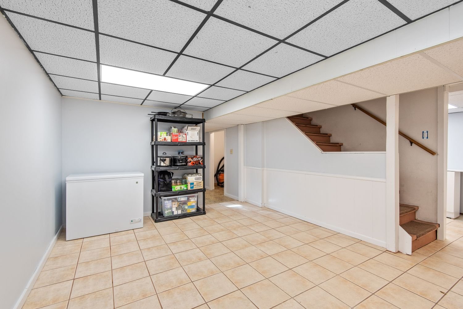 Basement with tiled floor, storage shelving and a staircase