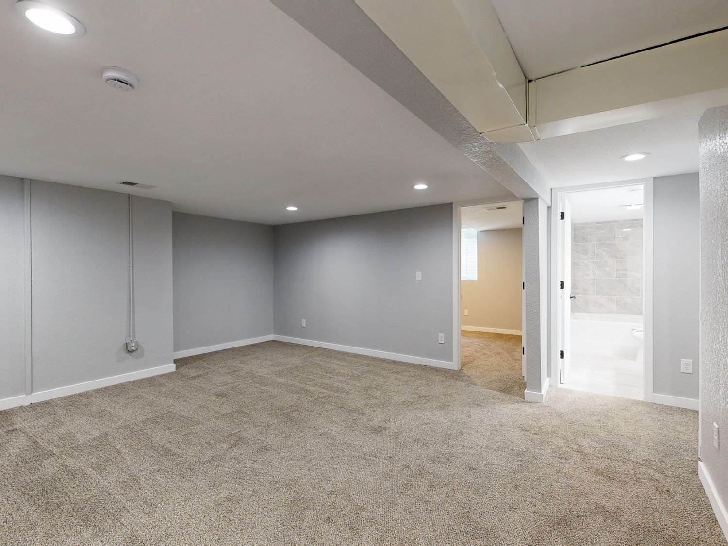 Empty basement room with neutral carpet and recessed ceiling lights