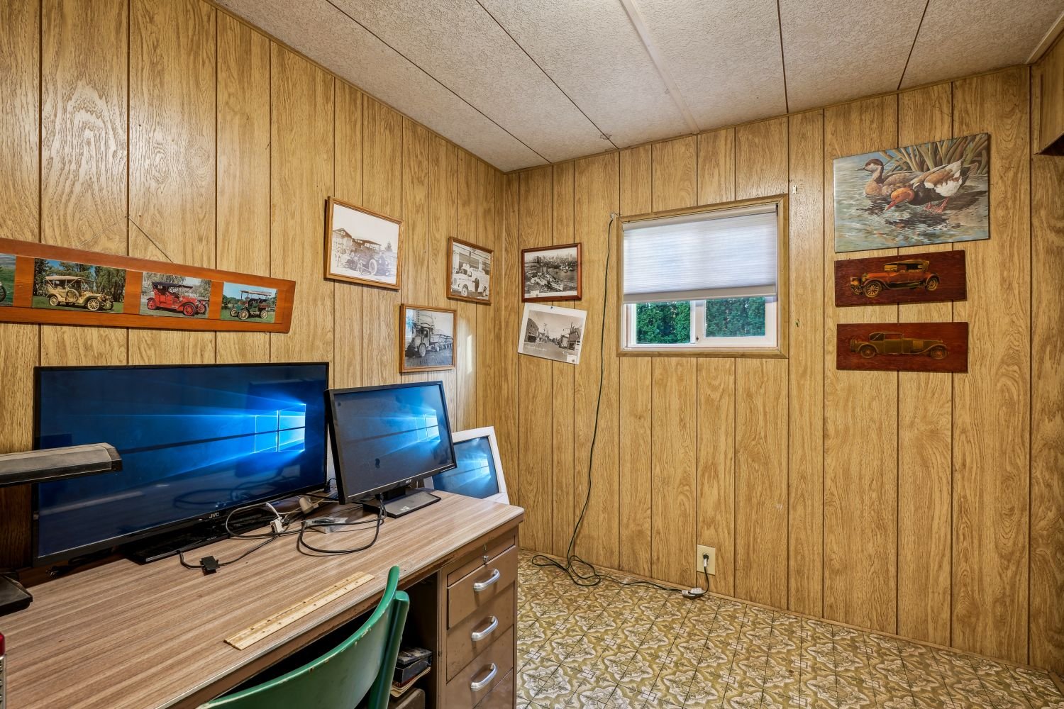 Basement home office with wood panelling and a dual monitor desk setup